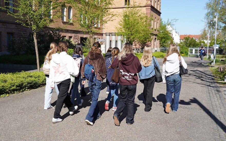Eine Gruppe von Mädchen läuft den Campusweg an einem Gebäude entlang.
