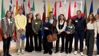 Eine Gruppe von Studierenden im Europäischen Parlament mit Flaggen im Hintergrund