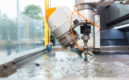 Die Wasserstrahlschneidanlage während des Schneidvorgangs in der Profilansicht.