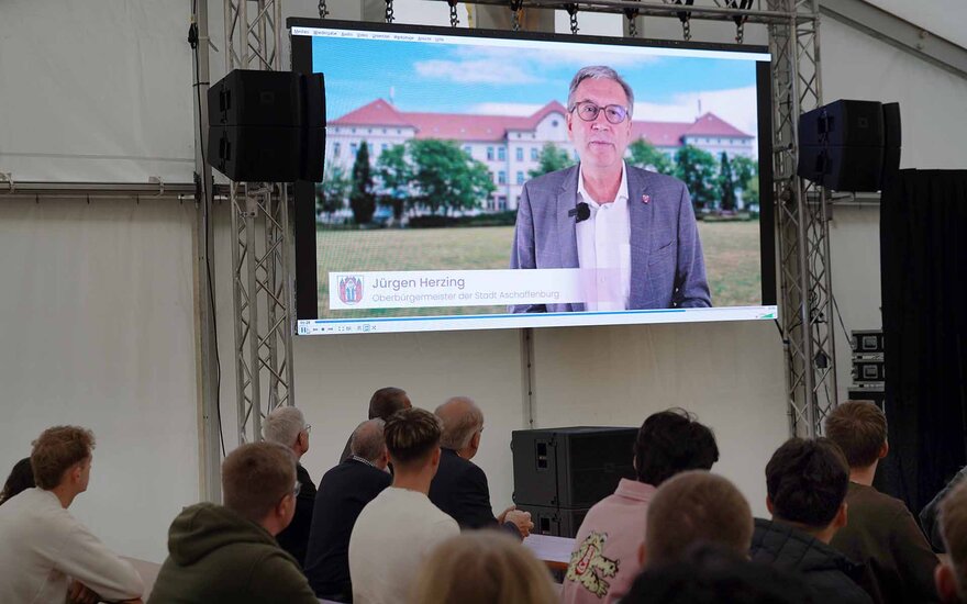 Video mit Oberbürgermeister auf Leinwand mit sitzenden Studierenden