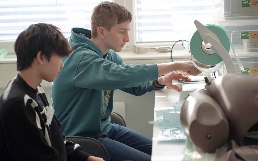 Zwei Jungen sitzen an einer Einschweißmaschine für Instrumente im SkillsLab.