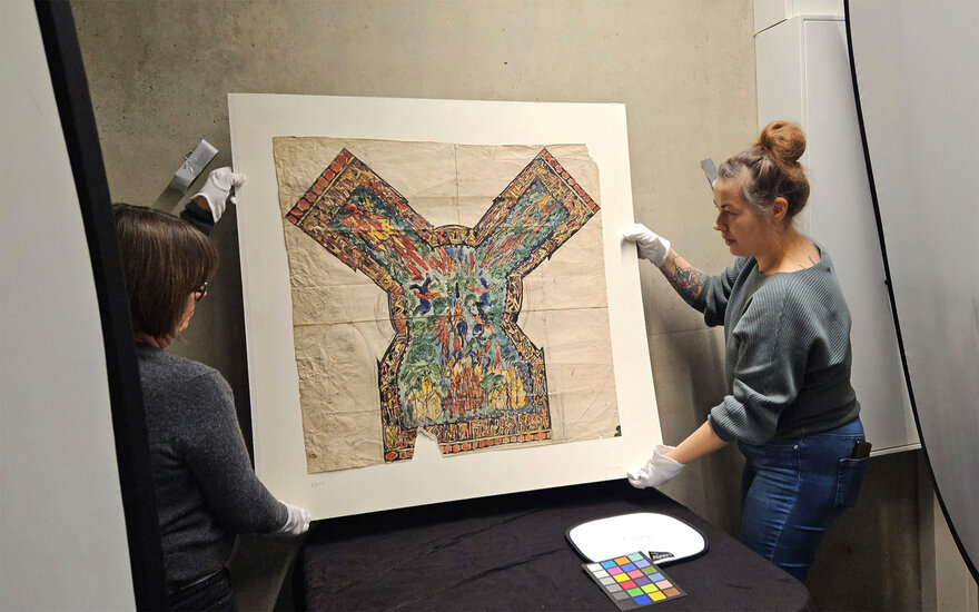 Zwei Frau halten Skizze vor eine Wand, um sie aufzuhängen