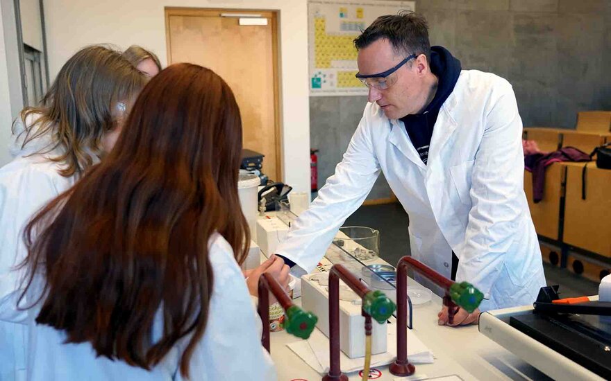 Teilnehmerinnen beim Girls Day beim Bearbeiten von Tonmasse gemeinsam mit Professor in weißen Kitteln