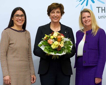 Die Präsidentin mit Blumenstrauß nach ihrer Wahl mit der Kanzlerin und der Hochschulratsvorsitzenden