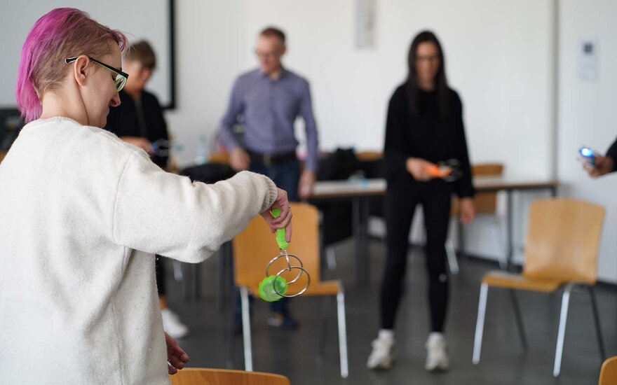 Personen stehen in eienm Vorlesungsraum und spielen etwas am Gesundheitstag.