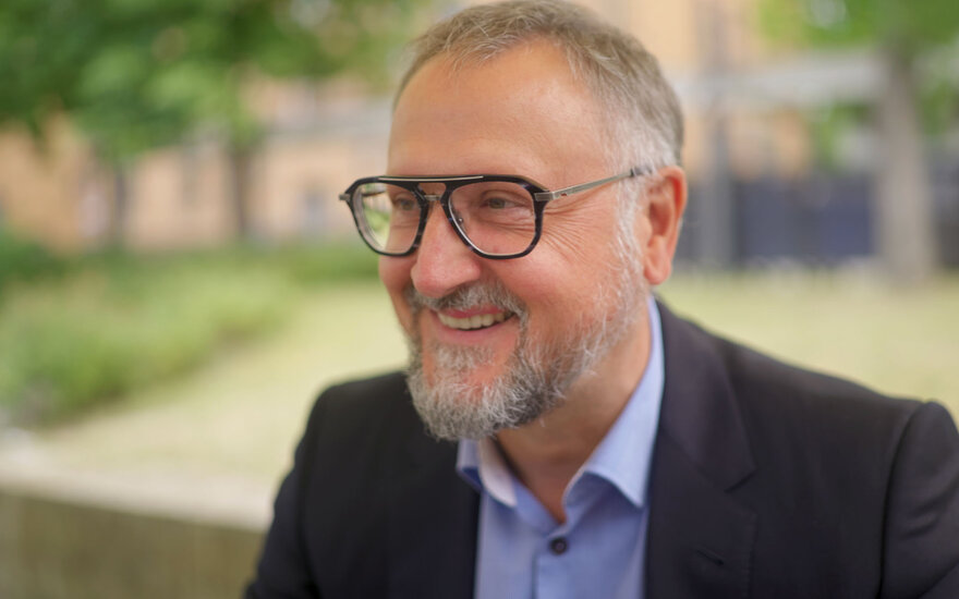 Nahaufnahme vom lächelnden Professor Lars Schöne vor dem Hochschulcampus