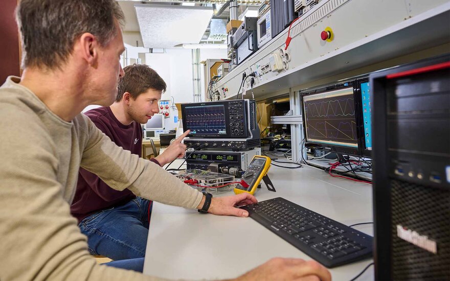 Mitarbeiter des Labors für Elektrische Maschinen, Leistungselektronik und Antriebe mit einem Spannungsmessgerät. 