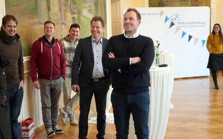 Timm steht neben Luca, Manuel und Prof. Zindler und schaut auf einen Bildschirm, der nicht zu sehen ist