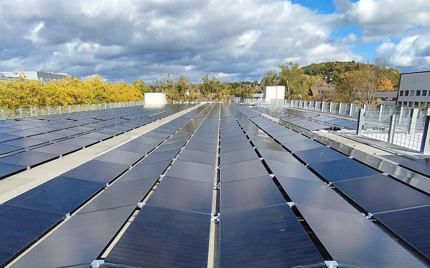 Die PV-Module auf dem Parkhausdach bei Sonnenschein mit Bäumen im Hintergrund