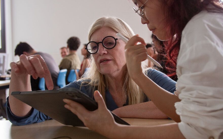 Professorin Barbara Sprick schaut zusammen mit einer Studentin auf einem Tablet und zeigt auf den Inhalt
