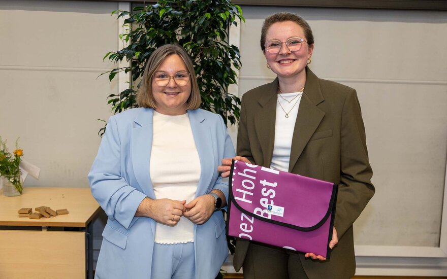 Dekanin und Absolventin stehen nebeneinander mit Mappe von TH in der Hand