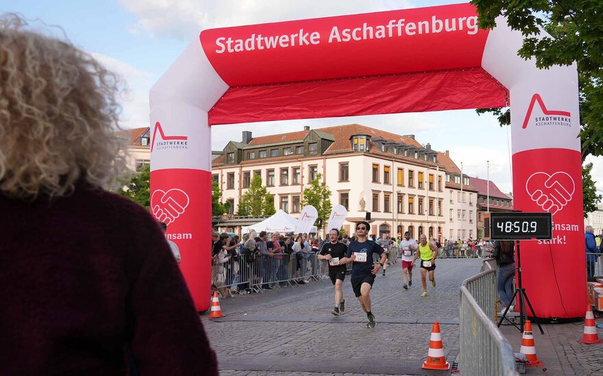 Zwei Läufer laufen durch rot-weiße Zielmarkierung auf Schlossplatz