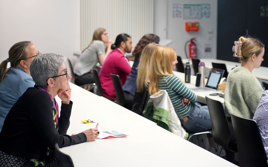 Personen sitzen in Hochschulhörsaal und hören einen Vortrag.