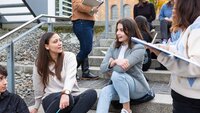 Internationale Austauschstudierende sitzen auf einer Treppe