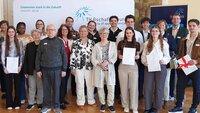 Gruppenfoto von Stipendiaten und Fördernden im Hocksaal vor TH-Logo-Wand