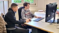 Zwei Jungs sitzen am Boys day in der Bibiliothek an einem Computer.