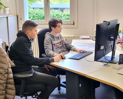 Zwei Jungs sitzen am Boys day in der Bibiliothek an einem Computer.