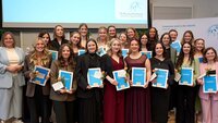 Gruppenbild der 23 Absolventinnen mit Urkunden und je einer Rose in der Hand zusammen mit Dekanin in der Aula