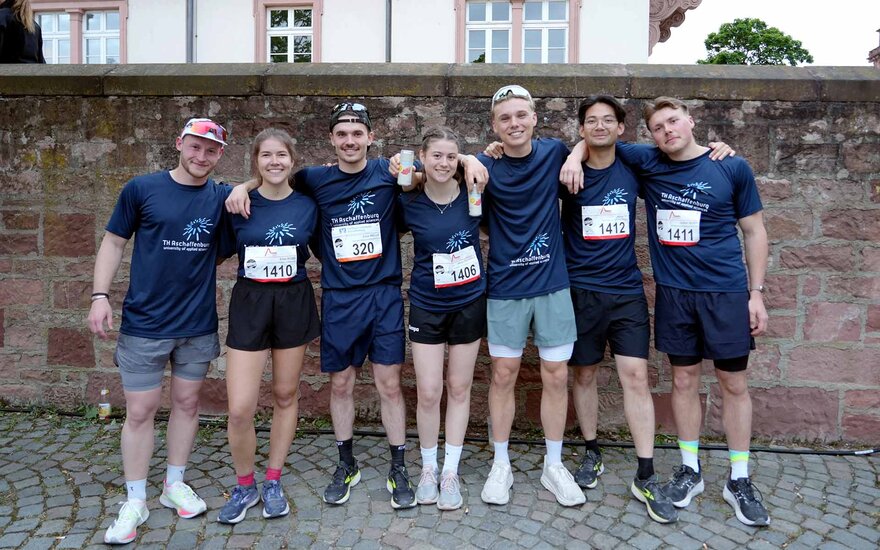 Studierende aus dem Laufteam der TH AB mit blauen T-Shirts mit Logo vor Mauer auf Schlossplatz