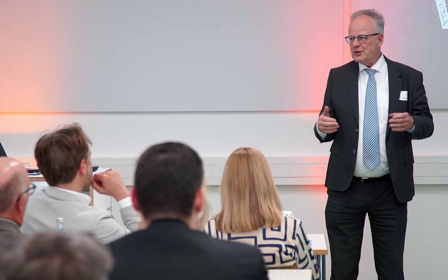 Dekan Webersinke im schwarzen Anzug spricht zu den sitzenden Gästen