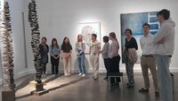 Studierende stehen im Halbkreis mit Präsidentin vor einem Kunstwerk