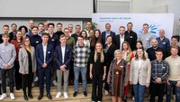 Die Stipendiatinnen und Stipendiaten des Deutschlandstipendiums zusammen mit ihren Fördernden vor der TH-Logo-Wand in der Aula