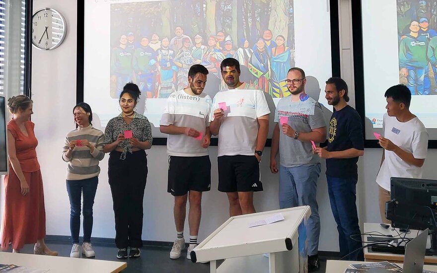 7 Studierende stehen nebeneinander vor der Leinwand mit Post-its in der Hand