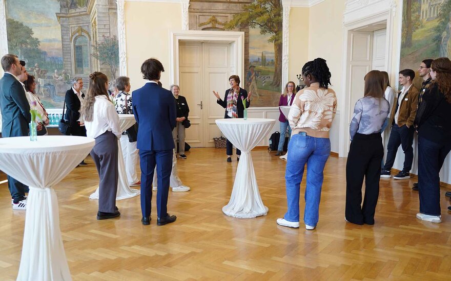 Stipendiaten und Fördernde stehen um die sie begrüßende Präsidentin herum