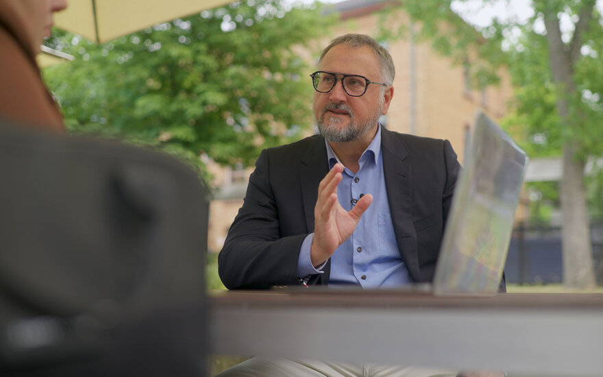 Professor Lars Schöne im Gespräch an einem Tisch auf dem Campus