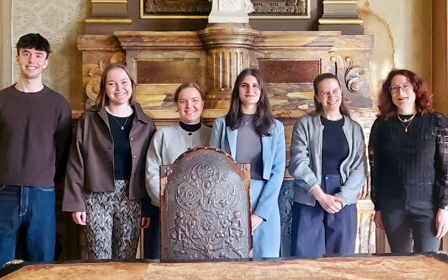 Ein Student und vier Studentinnen stehen neben Professorin 