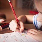 Kleinkind malt ein Blatt an einem Tisch aus