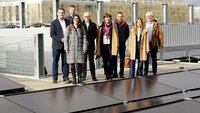 Gruppe von acht Personen steht auf dem Parkhausdach hinter der Solarpanelfläche
