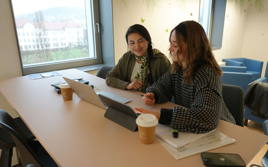Zwei Studentinnen arbeiten gemeinsam an ihren Laptops an einer Gruppenarbeit