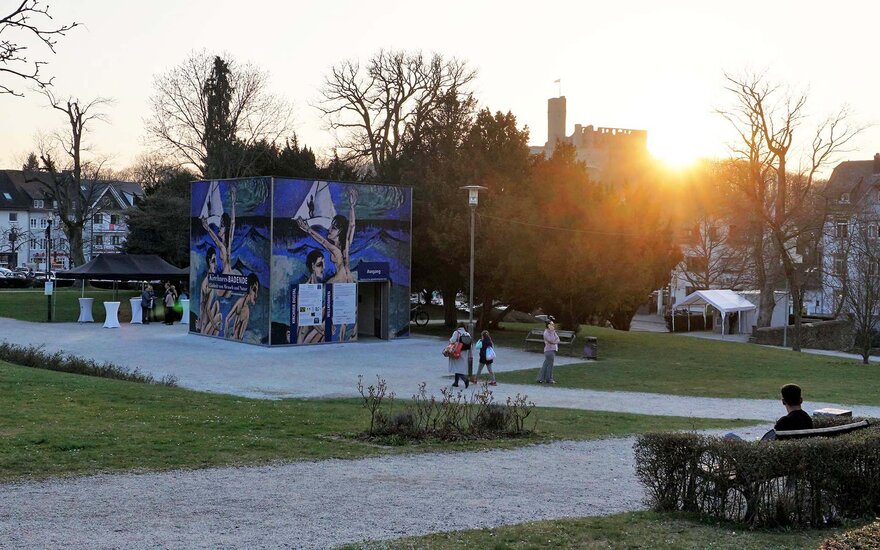 Ausstellungskubus mit Gemälden von Kirchner an der Außenwand und Besuchern der Eröffnung in Königstein