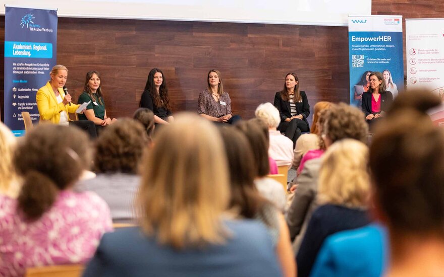 Fünf Frauen plus Moderatorin bei Diskussion auf Podium mit Publikum im Vordergrund