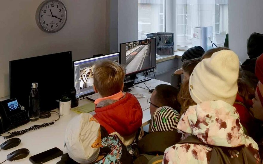 Die Kinder sitzen mit Blick auf die Bildschirme in der Schaltzentrale der Verkehrsbetriebe