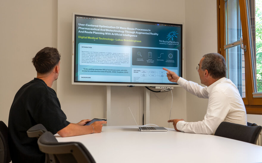 Lukas Boeddinghaus und Professor Doktor Jürgen Vaupel besprechen sein Forschungsprojekt vor einem großen Bildschirm