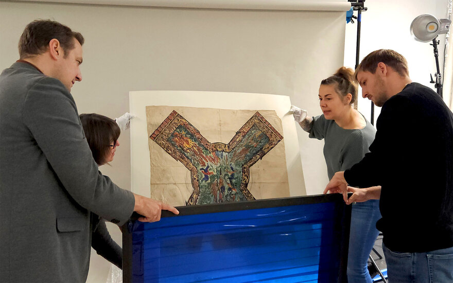 Zwei Männer und zwei Frauen heben Skizze aus einer Verpackung