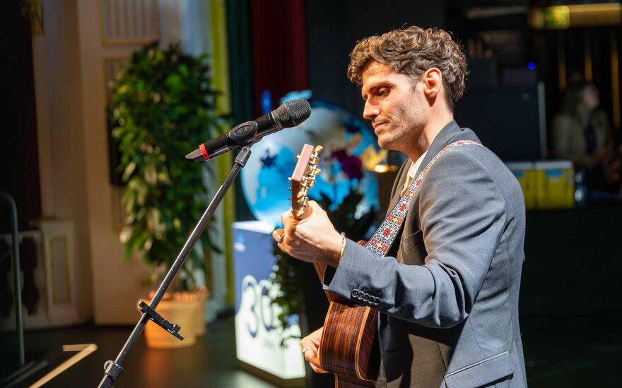 Junger Mann mit Gitarre in der Hand auf der Bühne