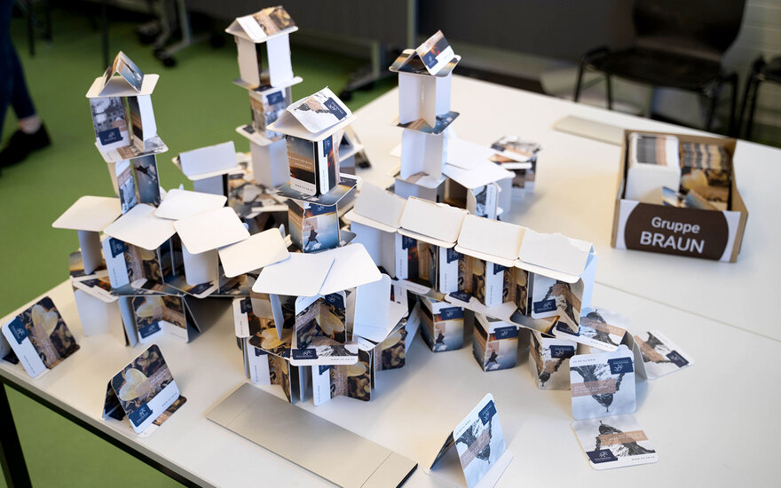 Auf einem Tisch stehen zu Gebäuden aufgetürmte Bierdeckel