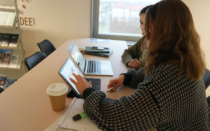 Zwei Studentinnen arbeiten gemeinsam an ihren Laptops an einer Gruppenarbeit