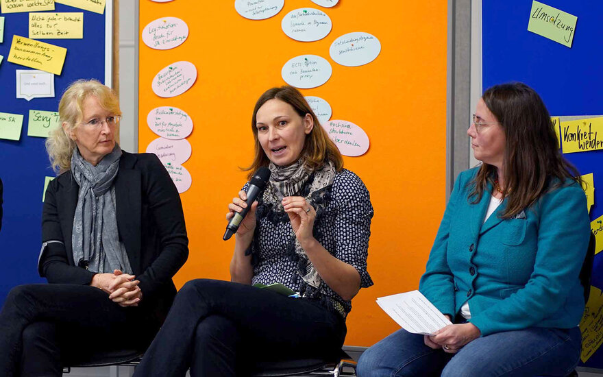 Drei sitzende Personen während Podiumsdiskussion