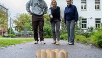 Drei Menschen spielen auf dem Campus ein Spiel.