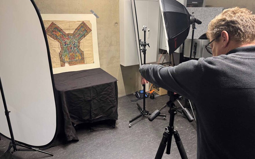 Mann im Fotostudio fotografiert mit Kamera auf Stativ Kirchnerskizze