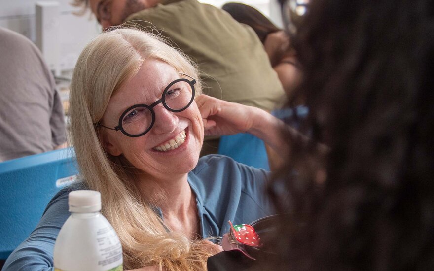 Professorin Barbara Sprick lächelt bei einer Unterhaltung mit einer Studentin, bei dieser nur der Hinterkopf sichtbar ist