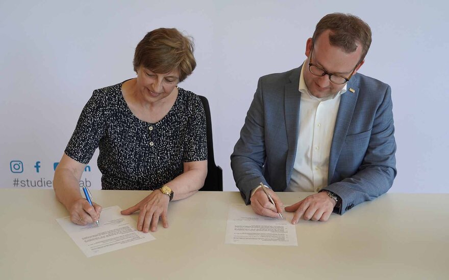 Präsidentin und BRK-Kreisgeschäftsführer am Tisch beim Unterschreiben des Vertrags