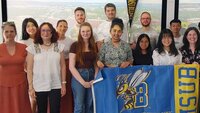 Gruppenfoto mit Gastprofessorinnen, Studierenden und blau-gelber Flagge der Montana State University 