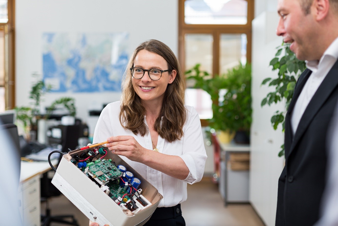 Frau zeigt Mann ein Forschungsprojekt. Im Hintergrund ist ein Büro.