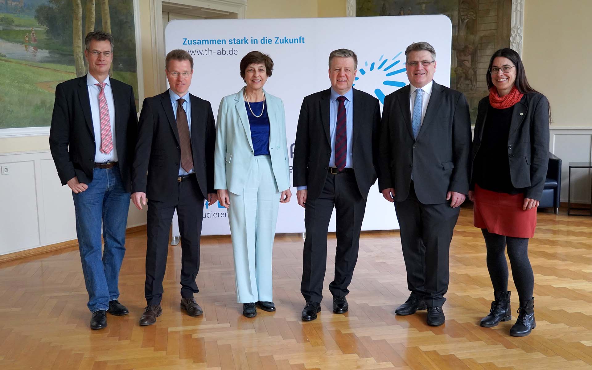 Die Hochschulleitung mit den beiden Landtagsabgeordneten vor der weißen Wand mit dem TH-Logo im Hocksaal