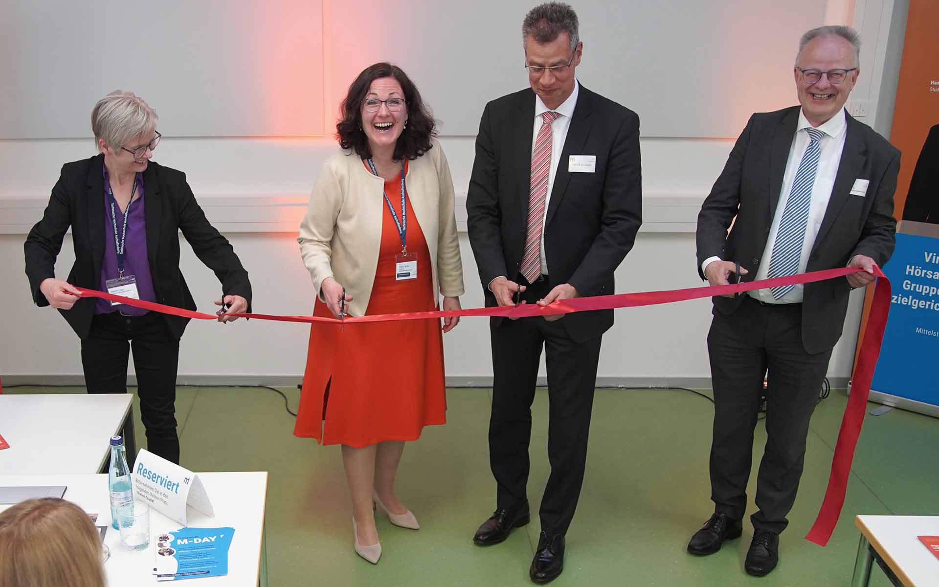 Fakultätsmitarbeiterin, Professorin, Vizepräsident und Dekan halten bzw. durchschneiden rotes Band
